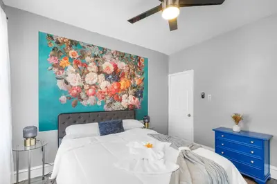 a bedroom with a painting of flowers on the wall at Bright Corner Flat near Transit and Trails in Philadelphia