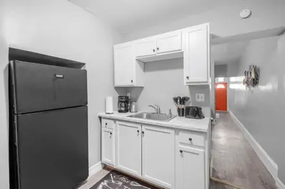 a kitchen with white cabinets and a black refrigerator at Bright Corner Flat near Transit and Trails in Philadelphia