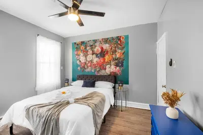 a bedroom with a painting of flowers on the wall at Bright Corner Flat near Transit and Trails in Philadelphia