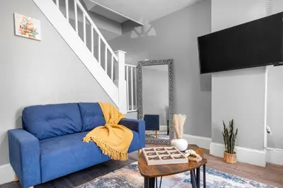 a blue couch in a living room with a staircase at Bright Corner Flat near Transit and Trails in Philadelphia