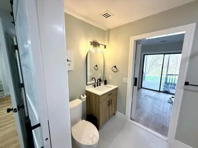 a bathroom with a toilet and a sink and a mirror at The Canopy 4BR Forest Escape Spa, Sip, and Unwind in Vernon Township