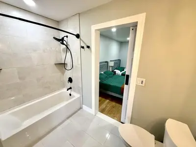 a bathroom with a bath tub and a bedroom at The Canopy 4BR Forest Escape Spa, Sip, and Unwind in Vernon Township