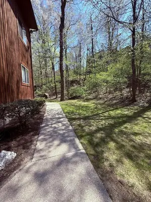a walkway next to a house in the woods at The Canopy 4BR Forest Escape Spa, Sip, and Unwind in Vernon Township
