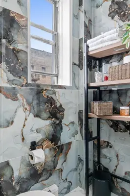 a bathroom with a marble wall with a window at Style & Comfort 3 Rooms -15 min from NYC in West New York