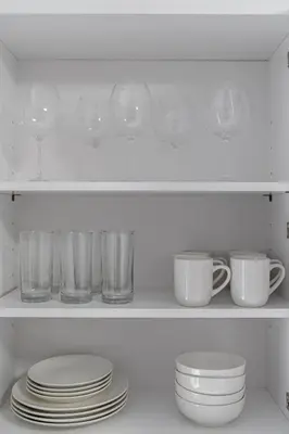 a white shelf with plates and cups and glasses at Style & Comfort 3 Rooms -15 min from NYC in West New York
