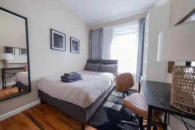 a small bedroom with a bed and a mirror at Sunny 4BR/2BA Retreat in Morningside Heights, NYC in New York