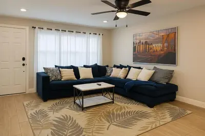 a living room with a blue couch and a ceiling fan at Group-Friendly Luxury 3BR 2 Baths Sleeps 8 in Irvington