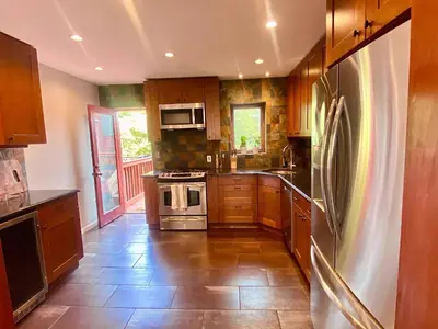 a kitchen with wooden cabinets and stainless steel appliances at Easy PATH&Bus access- NYC designer home & Terrace in Jersey City
