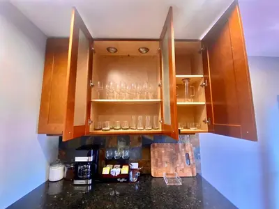 a kitchen with wooden cabinets with glasses on shelves at Comfortable home close to Manhattan,Wall St & more in Jersey City