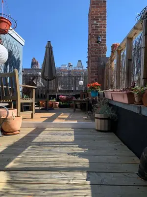 a patio with an umbrella and tables and benches at Airy brownstone penthouse duplex near Central Park in New York