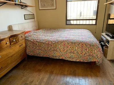 a bedroom with a bed and a dresser and a window at Airy brownstone penthouse duplex near Central Park in New York