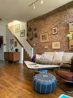 a living room with a couch and a brick wall at Airy brownstone penthouse duplex near Central Park in New York