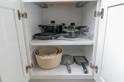 a cupboard with pots and pans in it at Style & Comfort 3 Rooms 15 min from NYC in West New York