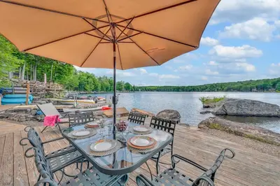 a wooden deck with a table with an umbrella at Lakefront at the Hideout in Lake Ariel