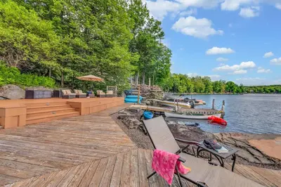 a wooden dock with chairs and a boat on the water at Lakefront at the Hideout in Lake Ariel