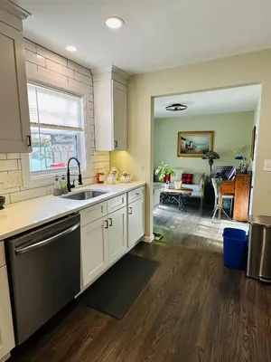 a kitchen with white cabinets and a sink and a living room at The Peaceful Perch Retreat Near NYC Elle's Home in Trenton