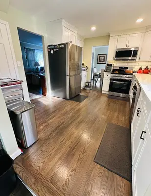 a kitchen with a stainless steel refrigerator and wooden floors at The Soft Landing Elle's Home Near NYC in Trenton