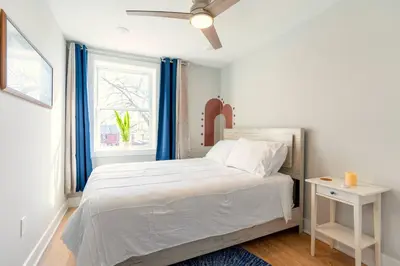 a white bedroom with a bed and a window at Elegant Urban Escape - 2 Bedrooms, 1 king Bed and 1 Queen Bed, Gated Private Entrance and Parking in Philadelphia