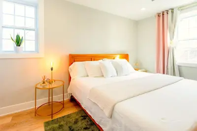 a bedroom with a large white bed and a window at Elegant Urban Escape - 2 Bedrooms, 1 king Bed and 1 Queen Bed, Gated Private Entrance and Parking in Philadelphia