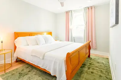 a bedroom with a large bed with white sheets at Elegant Urban Escape - 2 Bedrooms, 1 king Bed and 1 Queen Bed, Gated Private Entrance and Parking in Philadelphia