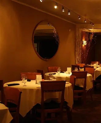 a restaurant with tables with white tablecloths and a mirror at Macaluso's at the Lantern Lodge in Jim Thorpe
