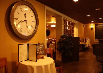 a clock on the wall of a restaurant with a table at Macaluso's at the Lantern Lodge in Jim Thorpe