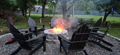 a fire pit in a yard with chairs and a table at Charming 3-BR Riverside country farmhouse Retreat Huge Yard & Fire Pit