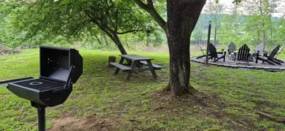 a laptop computer on a stand next to a tree at Charming 3-BR Riverside country farmhouse Retreat Huge Yard & Fire Pit