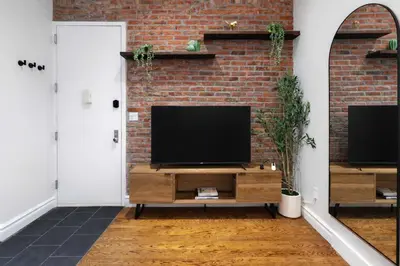 a living room with a television on a brick wall at Stylish Retreat in Prime West Village Spot in New York