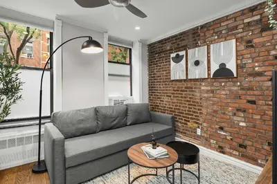 a living room with a couch and a brick wall at Trendy East Village Escape in New York