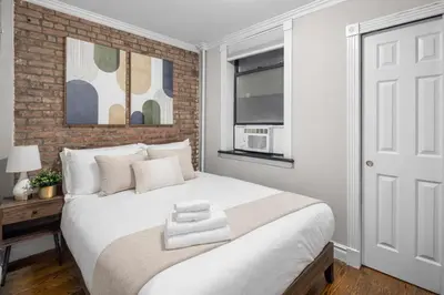 a bedroom with a white bed and a brick wall at Trendy East Village Escape in New York