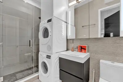 a bathroom with a washer and dryer in it at Modern West Village 1BR Garden steps to subway in New York