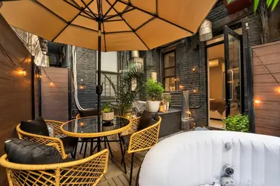 a patio with a table and chairs and an umbrella at Modern West Village 1BR Garden steps to subway in New York