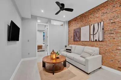 a living room with a couch and a brick wall at Modern West Village 1BR Garden steps to subway in New York