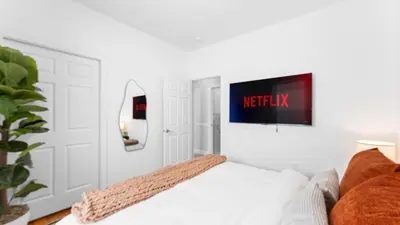 a bedroom with a bed and a tv on the wall at Luxury Retreat Walk 2 PATH NYC in Mins Parking in Jersey City