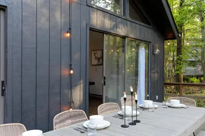 a wooden table with plates and candles on a patio at Luxurious Cabin by Lakes & Ski in Lake Ariel