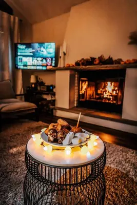 a table with a plate of food in a living room with a fireplace at Luxurious Cabin by Lakes & Ski in Lake Ariel