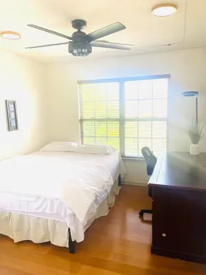 a bedroom with a bed and a desk and a ceiling fan at Aum Quite Heaven Stay in Monroe Township