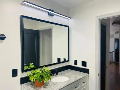 a bathroom with a large mirror above a sink at Aum Quite Heaven Stay in Monroe Township