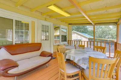 a living room with a couch and a table on a porch at Screened Porch and Fire Pit Cabin Near Bethel Woods in Mongaup Valley