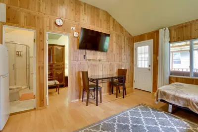 a bedroom with a table and a bed and a bathroom at Screened Porch and Fire Pit Cabin Near Bethel Woods in Mongaup Valley