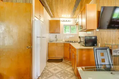 a small kitchen with wooden cabinets and a microwave at Community Perks Mongaup Valley Cabin with Grill! in Mongaup Valley