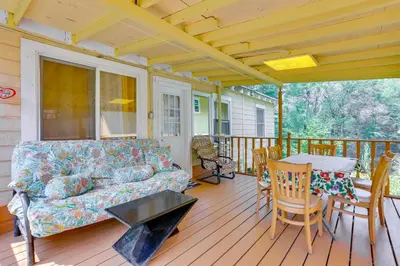 a living room with a couch and a table on a porch at 5 Mi to Swinging Bridge Reservoir Cabin with Porch! in Mongaup Valley