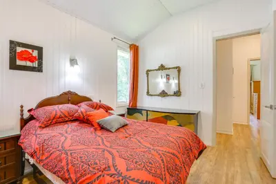 a bedroom with a bed with a red comforter and a mirror at 6 Mi to State Park Mongaup Valley Cabin! in Mongaup Valley