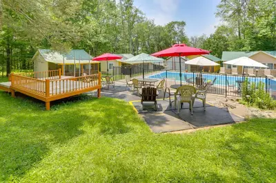 a patio with tables and umbrellas next to a pool at 6 Mi to State Park Mongaup Valley Cabin! in Mongaup Valley