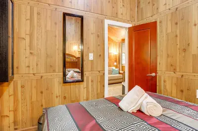 a bedroom with wooden walls and a bed with towels at 5 Mi to Monticello Raceway Cabin Near Shops in Mongaup Valley
