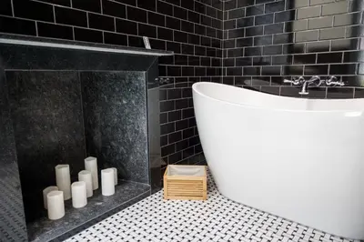 a bathroom with a white tub and black tiles at The Gas Lamp Hotel in Philadelphia