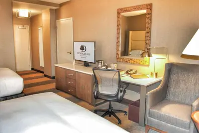 a hotel room with a desk and a bed and a room with a mirror at DoubleTree by Hilton Hotel Reading in Reading