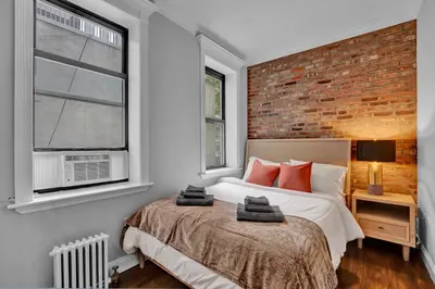 a bedroom with a bed and a brick wall at Stylish 3BR-2BA in Gramercy -Modern & Central in New York