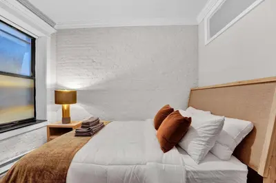 a bedroom with a large white bed with a window at Stylish 3BR-2BA in Gramercy -Modern & Central in New York